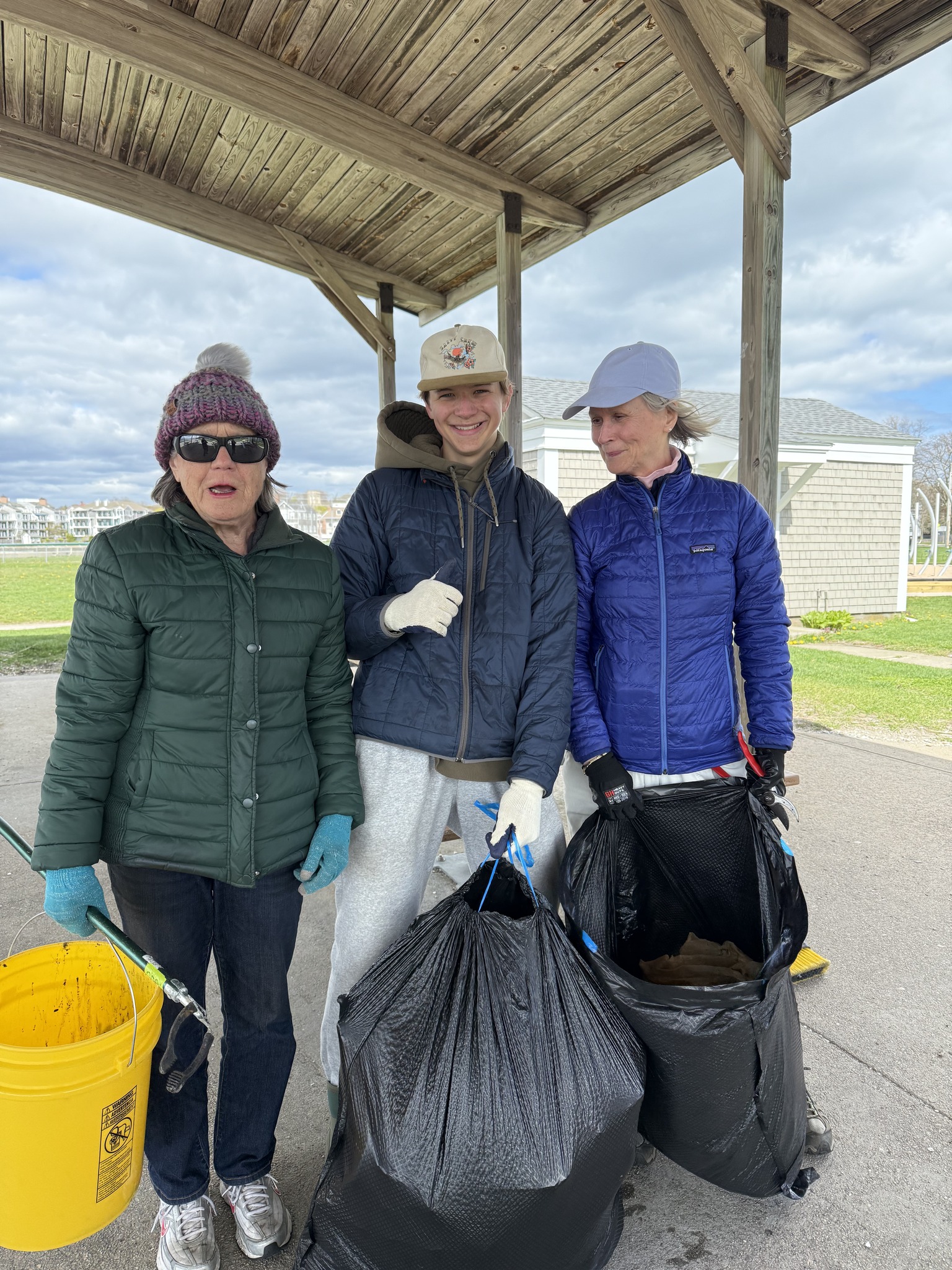 3 volunteers posed at the park with trash bags and buckets for cleaning